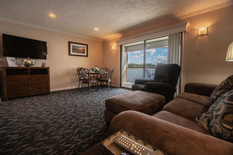 Photo of living room with accent chair, three seat sofa, dining table and TV. Unit 125