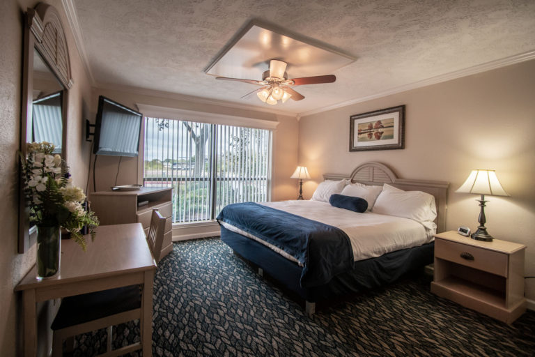 Photo of bedroom with ceiling fan, king bed, tv, drawer, two night stands. Unit 125