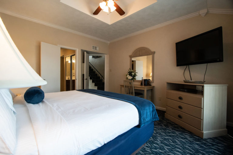 Photo of bedroom with TV, drawer, and mirror. Room 225