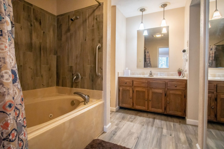 Photo of bathroom with bathtub, wall mirror and sink. Room 225